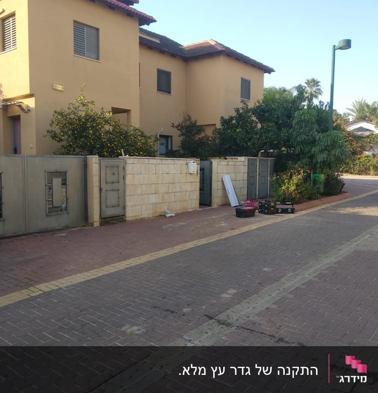 כלי עבודה וקרשים ליד גדר אבן בגינה